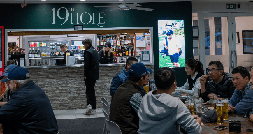 Golf club digital screen in the clubhouse while people relax post-round of golf